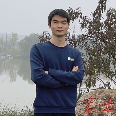 A young asian male shown from the hips up. He has dark hair and is wearing a long sleeve dark blue shirt. Behind him is a misty lake and some trees.